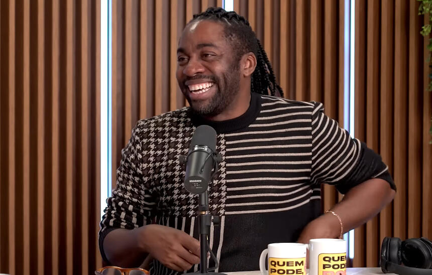 Lázaro Ramos sorrindo, sentado, durante entrevista para o Quem Pode Pod