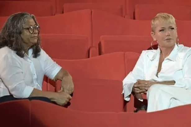 Xuxa e Marlene Matos sentada em arquibancada durante gravação de entrevista