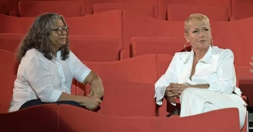 Xuxa e Marlene Matos sentada em arquibancada durante gravação de entrevista