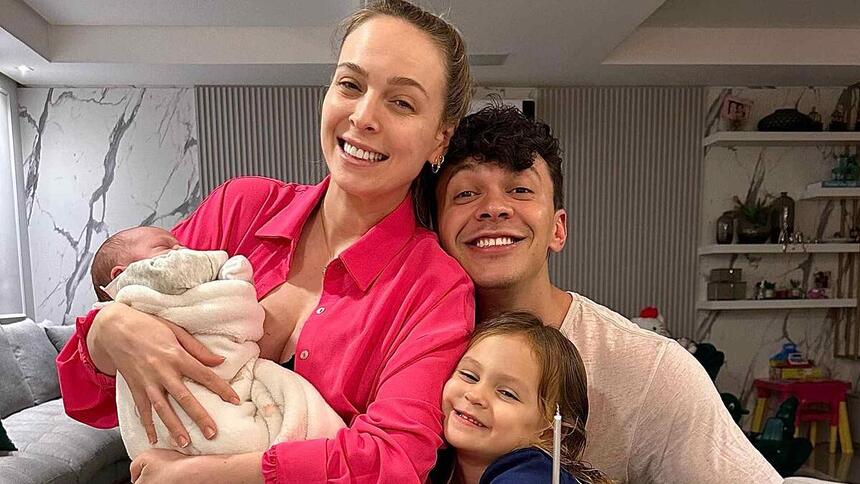 Tata Estanieck e Julio Cocielo sorrindo, abraçados com os filhos durante registro fotográficos em casa