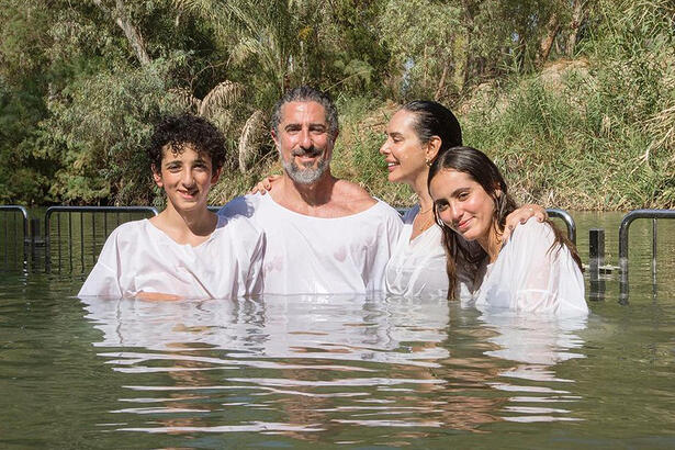 Famíla de Marcos Mion de camisa branca, sorrindo, durante batismo