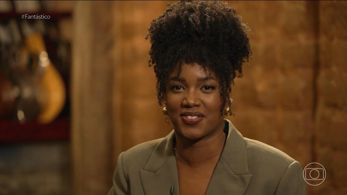 Cantora IZA sorrindo em entrevista no Fantástico