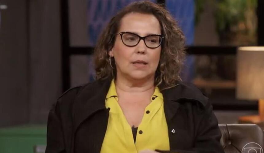 Ana Beatriz Nogueira de camisa social amarela e blazer preto, sentada em frente a Pedro Bial durante gravação de entrevista