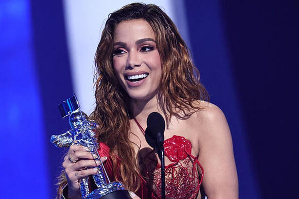 Anitta de vestido vermelho e lace ruiva segurando a estatueta do VMAs