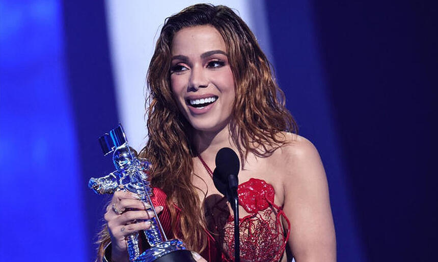 Anitta de vestido vermelho e lace ruiva segurando a estatueta do VMAs