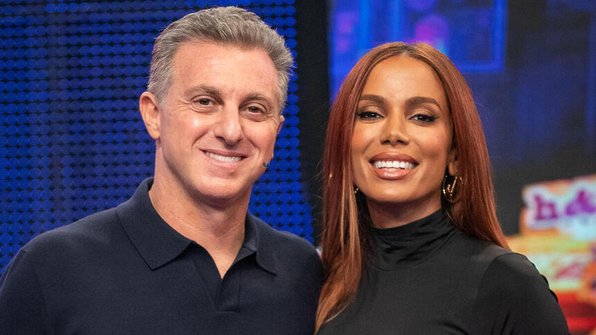 Anitta e Luciano Huck abraçados no palco do Domingão