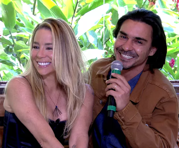 Danielle Winits e André Gonçalves sorrindo, sentados, durante gravação do Mais Você, em 2016