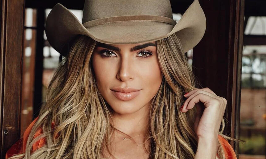 Erika schneider de chapéu de cowboy marrom, usando top laranja, cabelo solto durante ensaio fotográfico