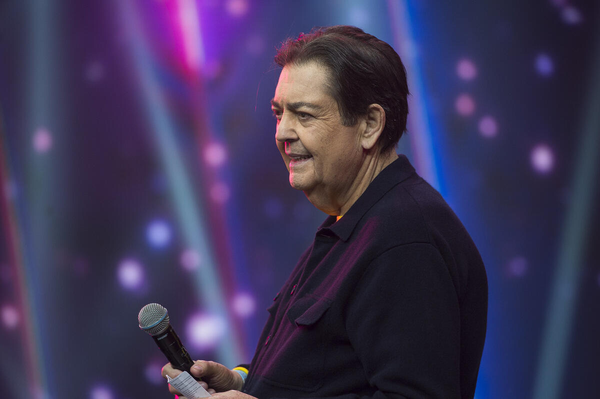 Faustão sorrindo no cenário da Band