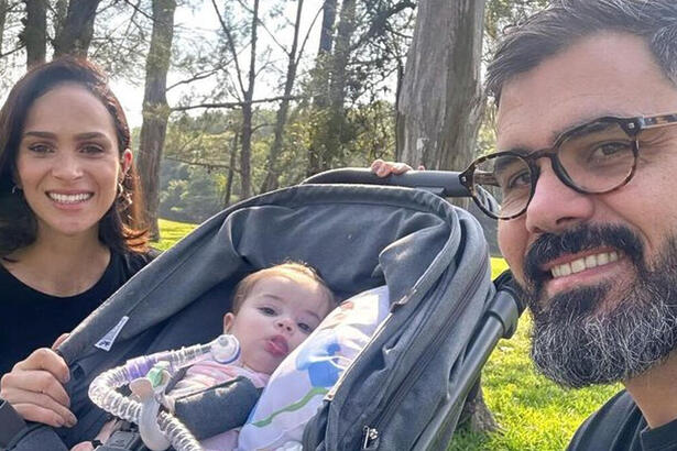 Juliano Cazarré e Leticia Cazarré em foto posada ao lado da filha, no carrinho e com o tubo de traqueostomia