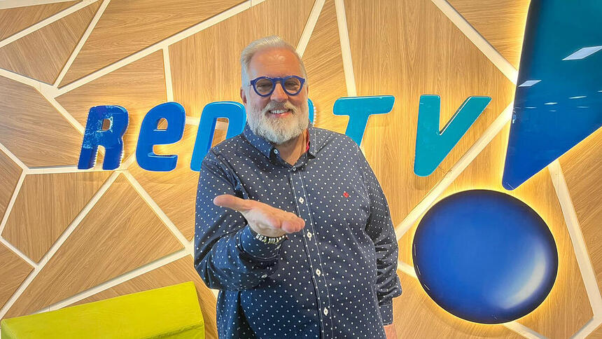 Leão Lobo posando em frente ao logo da RedeTV!