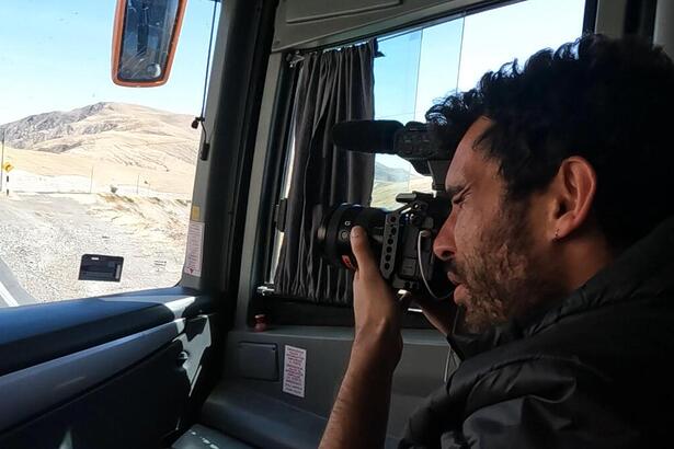 Cinegrafista registrando na frente do ônibus a estrada da viagem, em trecho do Profissão Repórter