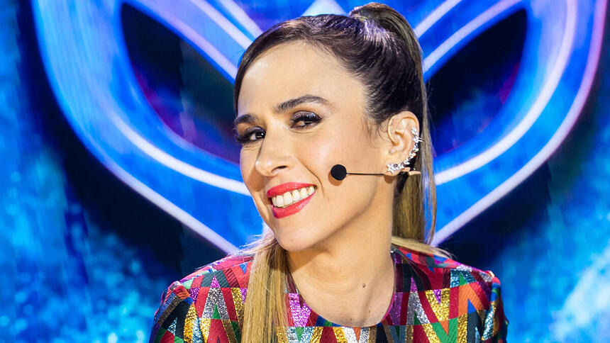 Tatá Werneck sentada na bancada do The Masked Singer Brasil