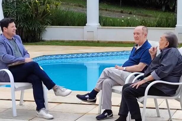 Michael Keller entrevista Renato Aragão, o Didi, e Dedé Santana em homenagem na Record. Os três estão sentados na beira da piscina