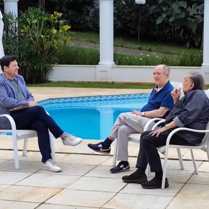 Michael Keller entrevista Renato Aragão, o Didi, e Dedé Santana em homenagem na Record. Os três estão sentados na beira da piscina