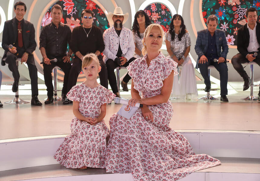 Manu, filha de Eliana sentada ao lado da apresentadora no palco do programa do SBT