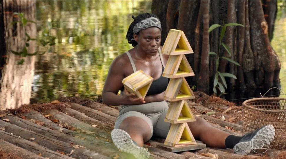 Greici sentada equilibrando triangulos durante prova da imunidade