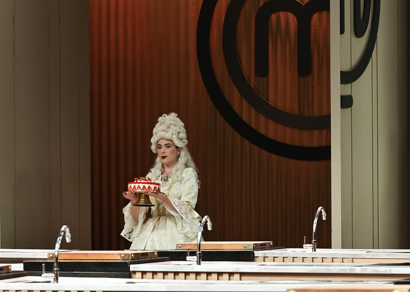 Entrada triunfal de uma personagem representando a rainha Maria Antonieta, que traz nas mãos um de seus doces preferidos: o bolo fraisier 