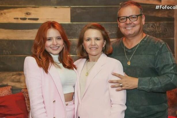 Larissa Manoela de terninho rosa e cabelo ruivo abraçada aos pais Silvana e Gilberto