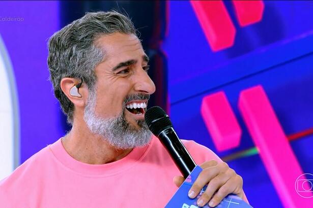 Marcos Mion de camisa rosa e sorrindo no Caldeirão