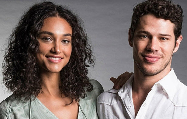 Debora Nascimento de camisa cinza, sorrindo, de cabelo solto, ao lado de José Loreto, sorrindo, de camisa branca, durante ensaio fotográfico para a TV Globo