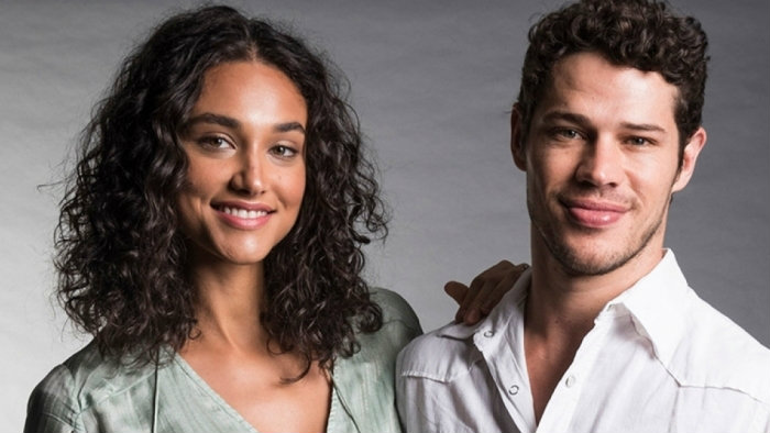 Debora Nascimento de camisa cinza, sorrindo, de cabelo solto, ao lado de José Loreto, sorrindo, de camisa branca, durante ensaio fotográfico para a TV Globo