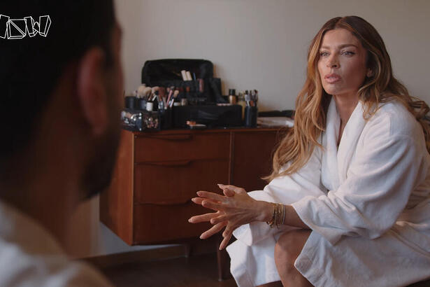 Grazi Massafera de roupão, de cabelo solto, maquiada, sentada durante entrevista