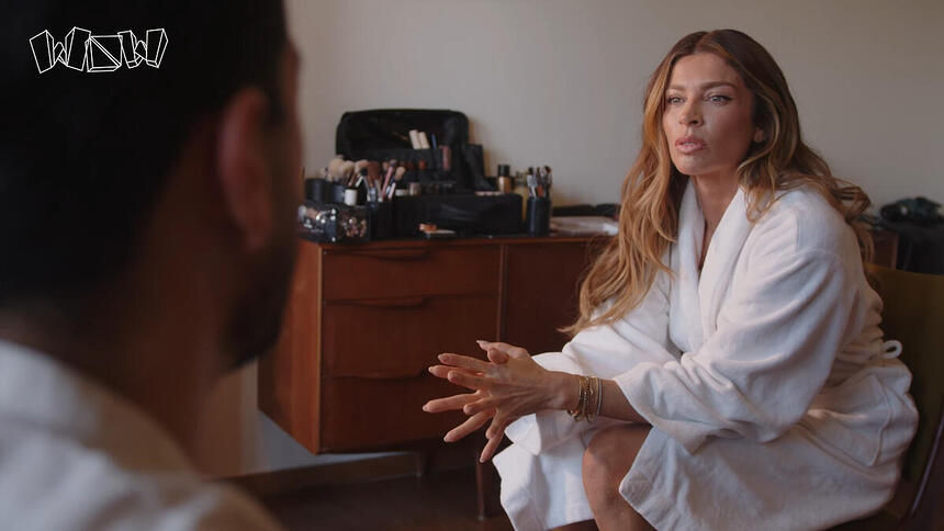 Grazi Massafera de roupão, de cabelo solto, maquiada, sentada durante entrevista