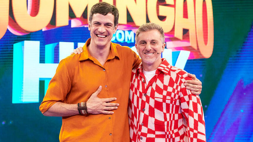 Mateus Solano e Luciano Huck em foto posada no cenário do Domingão