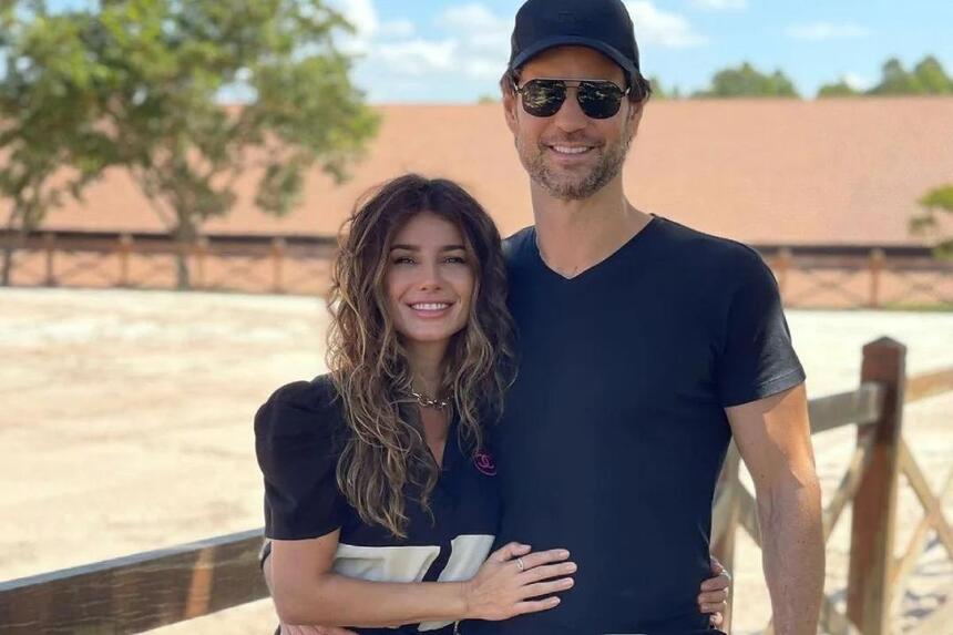 Paula Fernandes e Rony Cecconello de camisa preta, sorrindo, abraçados num haras