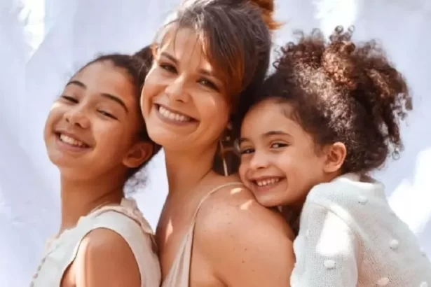 Samara Felippo sorrindo, de vestido bege, abraçada com as filhas em ensaio fotográfico