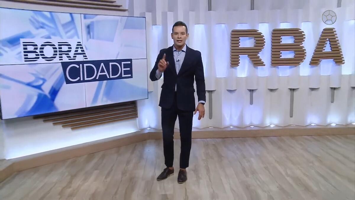 Agenor Santos levanta o dedo enquanto anda no estúdio do Bora Cidade, da RBATV, afiliada da Band