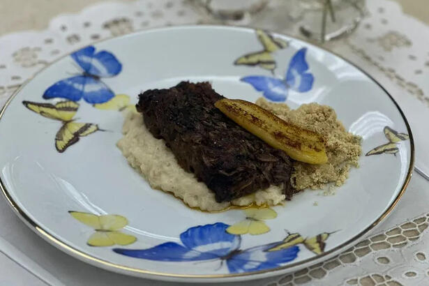 Carne braseada com pirão de leite no prato do É de Casa