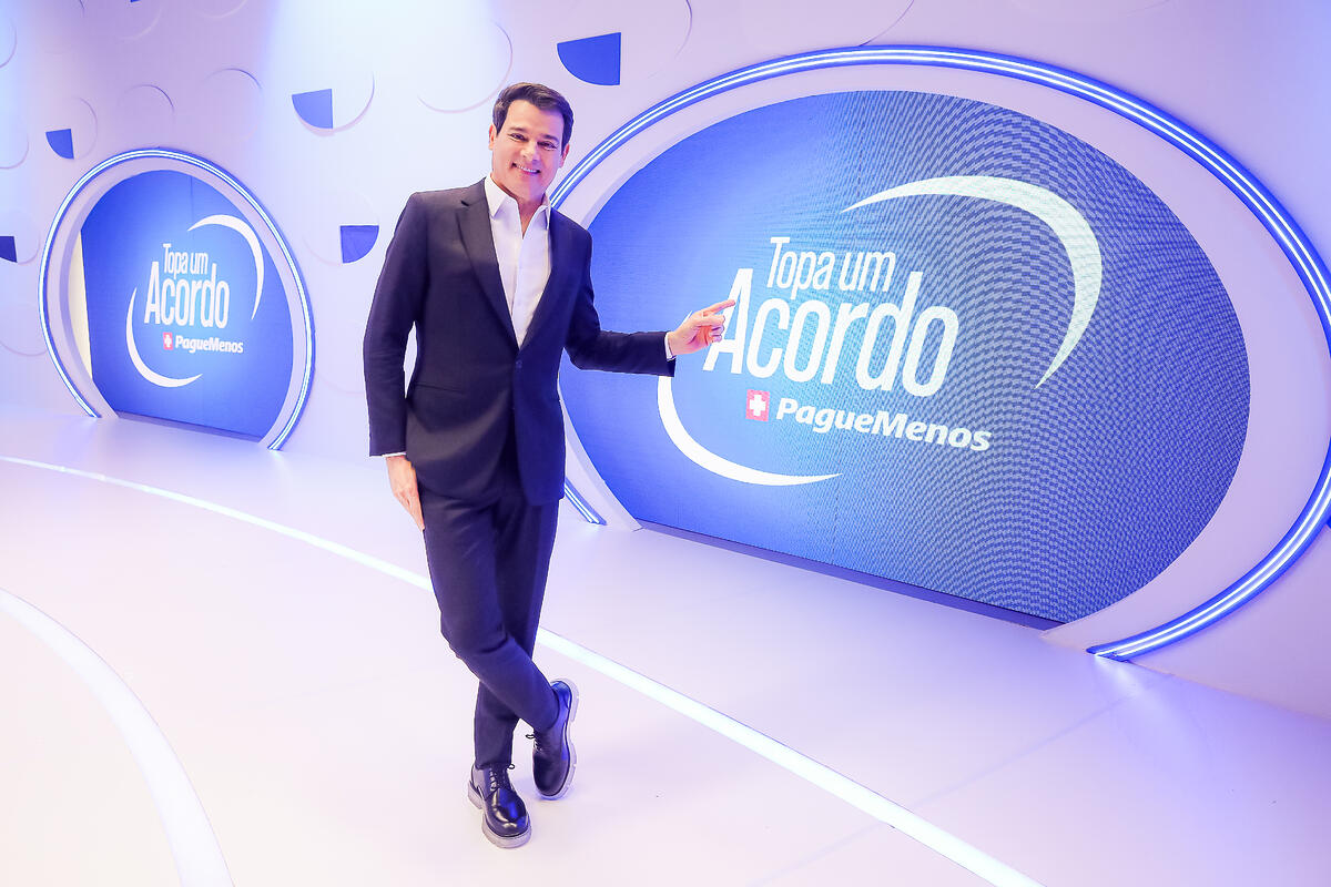 Celso Portiolli aponta para o logo do programa Topa um Acordo Pague Menos