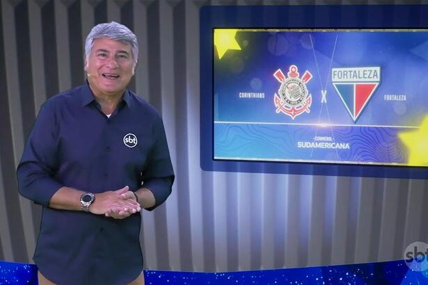 Cleber Machado no estúdio da Copa Sul Americana, na frente de uma tela com o logo do Corinthians e Fortaleza