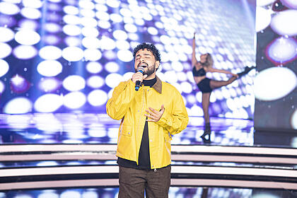 Gabriel Henrique de jaqueta amarela canta no palco do Hora do Faro