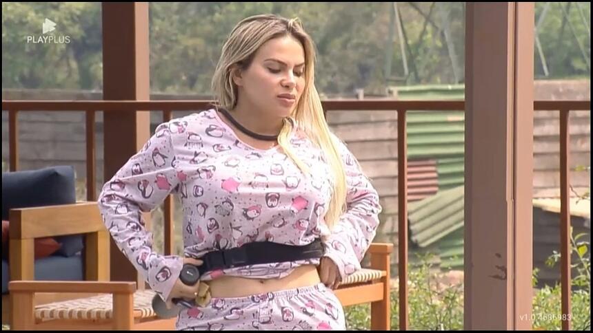 Kally de pijama ajeitando o microfone enquanto conversa com peões na piscina de A Fazenda