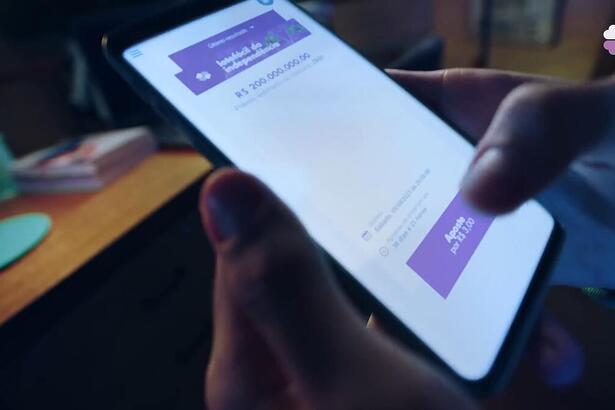 Mão mexe em um celular que mostra a Lotofácil da Independência