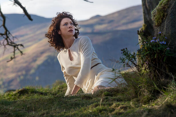 Claire, protagonista de Outlander, de vestido branco, olhando para o céu