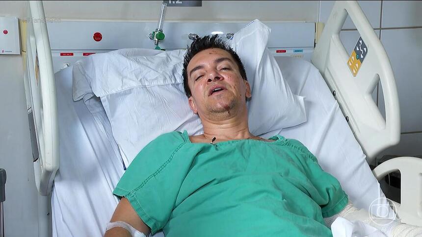 Regis Danese com roupa de hospital verde deitado na cama do HUGOL