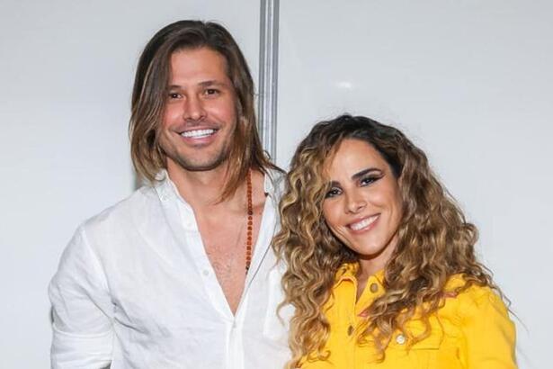 Dado Dolabella de camisa social branca, sorrindo, de cabelo solto, abraçado com Wanessa, que está de cabelo enrolado, sorrindo, de camisa amarela