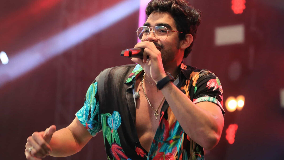 Gabriel Diniz usando camisa estampada colorida durante apresentação no palco