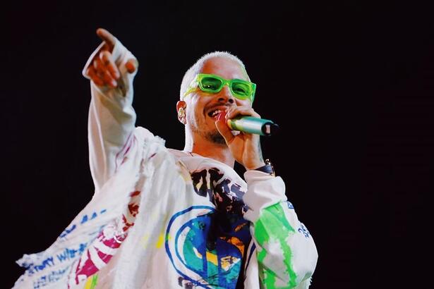 J Balvin de cabelo verde segurando um microfone durante show