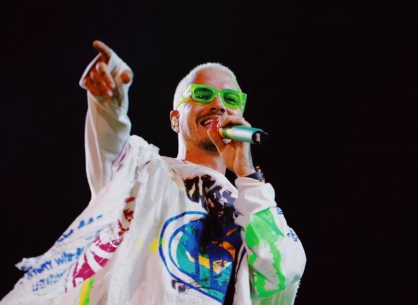 J Balvin de cabelo verde segurando um microfone durante show