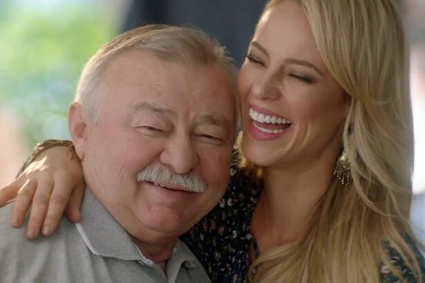 Paolla Oliveira de cabelo loiro, liso, sorrindo, abraçando o pai durante gravação de publicidade