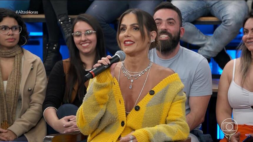 Deborah Secco de blusa amarelo segurando o microfone do Altas Horas