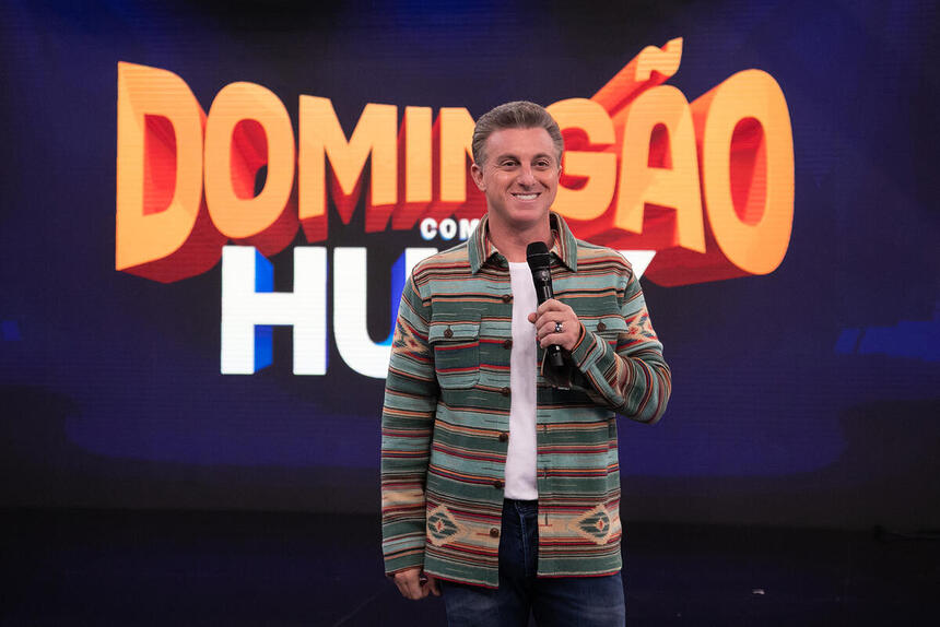 Luciano Huck sorrindo no cenário do Domingão