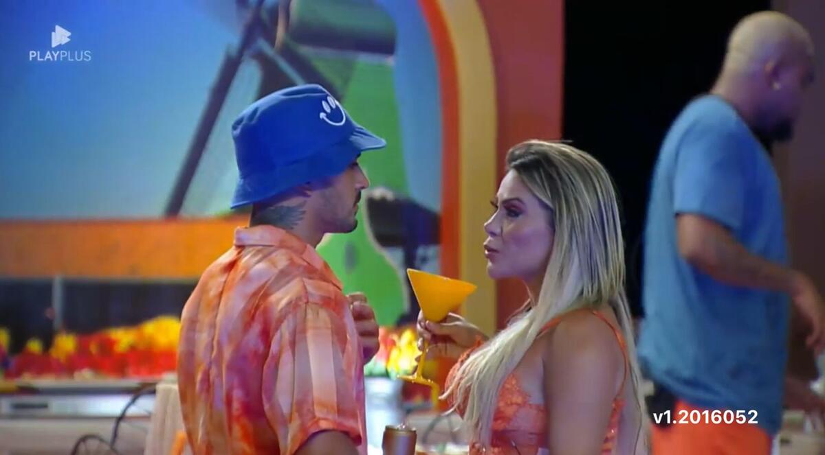 Yuri com um chapéu azul na cabeça conversa com Kally durante festa de A Fazenda.