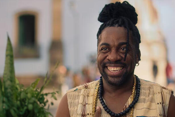 Lázaro Ramos sorrindo, com cabelo de dread, caracterizado durante gravação do filme Ó Pai Ó 2