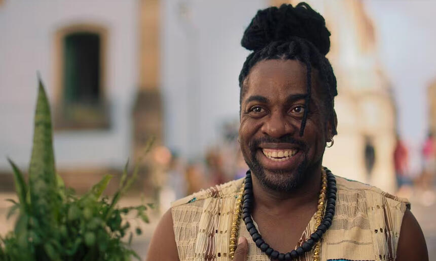 Lázaro Ramos sorrindo, com cabelo de dread, caracterizado durante gravação do filme Ó Pai Ó 2